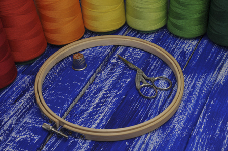 Hoop, scissors and colored threads for sewing and embroidery on the background of a wooden tableの写真素材
