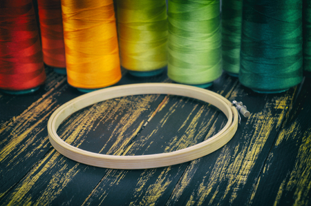 wooden hoop close up on a background of colorful spools of thread on the old tableの写真素材