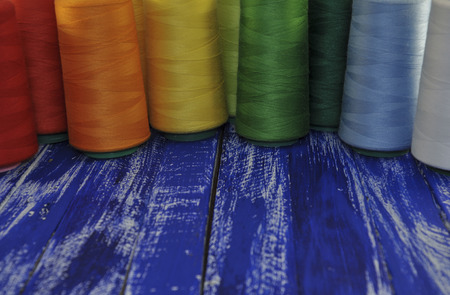 multi-colored coils for sewing and embroidery on the background of the old wooden tableの写真素材