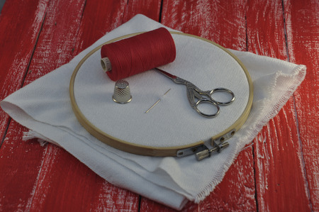 The fabric in the hoop for the embroidery with a reel of red threadの写真素材