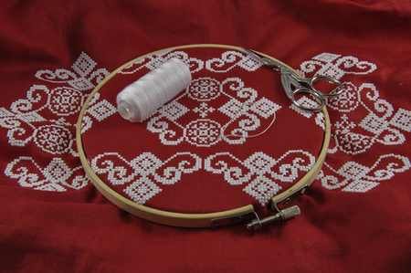 Red cloth embroidered with a cross in the wooden hoopの写真素材