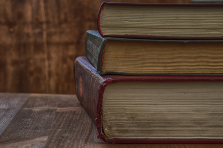 Vintage photo of books of different thicknesses on a wooden tableの写真素材