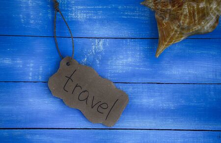 vintage wooden blue background with sea shells and a piece of paper with travelの写真素材