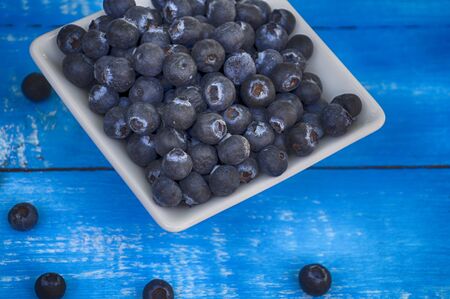 Blueberries in a bowl on a background of blue vintage wooden table