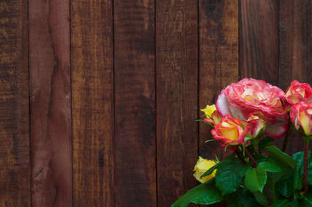bouquet of yellow and pink roses on the background blurred brown wooden retro backgroundの写真素材