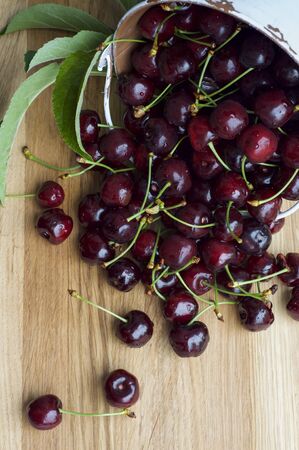 Cherry crumbled from a bucket on a wooden table
