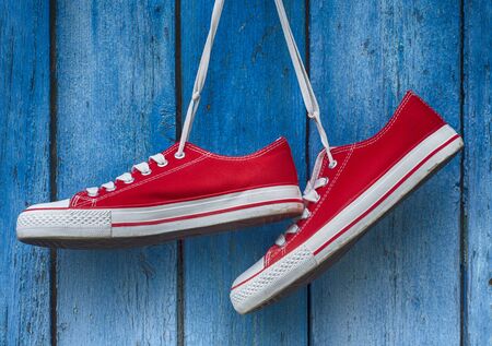 pair sneakers hanging on a wooden old retro blue backgroundの写真素材