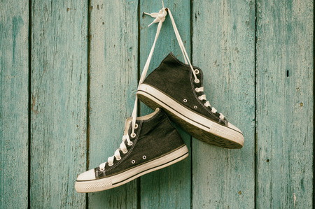 Dark blue sneakers hang on a nail on a blue wooden wall, canvas shoe,toningの写真素材