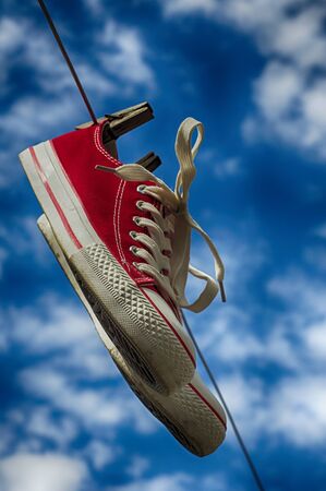 pair of red sneakers on a clothesline on a blue sky backgroundの写真素材