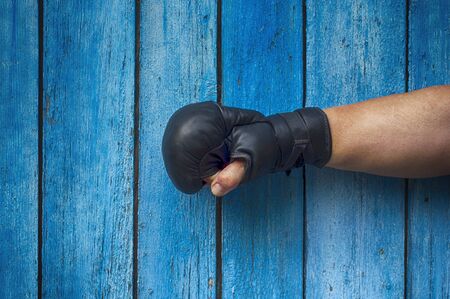 right hand of the man in black boxing gloves on a blue retro wooden backgroundの写真素材