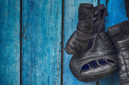 Black gloves for kickboxing hanging on wooden blue wallの写真素材