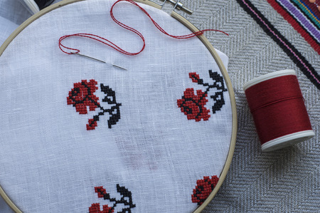 Traditional folk embroidery cross on a wooden hoop, floral motif