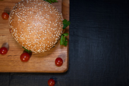 Delicious fresh hamburger on a chopping board and cherry tomatoes, top view, selective focus