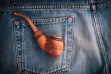 Wooden pipe for tobacco is in the back pocket of old blue jeans, a top viewの写真素材