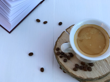 cup of coffee and open book on a white wooden background, empty spaceの写真素材