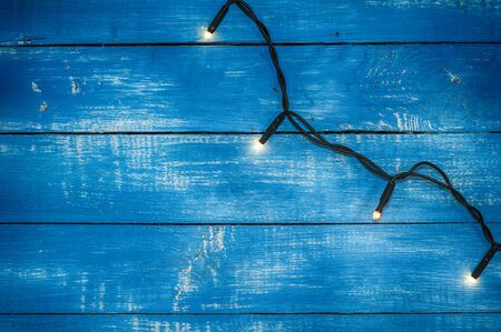 Electric garland with small paws on a blue wooden background, vintage toningの写真素材