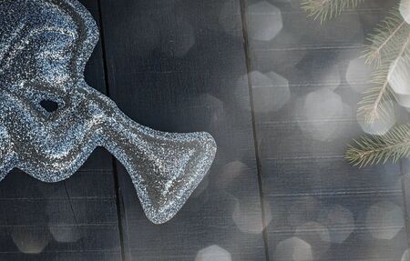 brilliant figure of an angel with a trumpet on a black wooden background, near a branch of spruce
