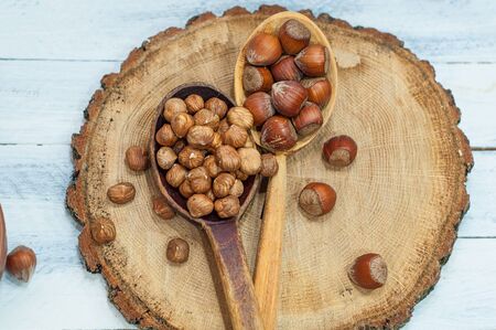 Hazelnut in wooden spoon, in the shell and For shelled on a wooden stump, top viewの写真素材
