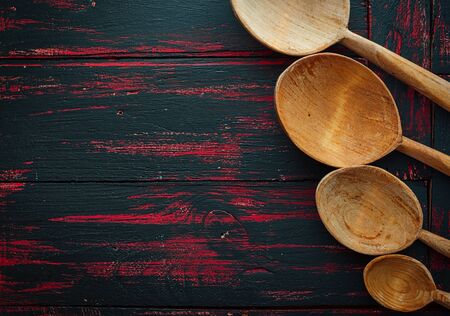 Four empty wooden spoon on wooden surface, top view, an empty space