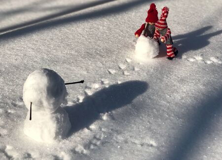 Small wooden doll in the scene of building a snowman, close upの写真素材