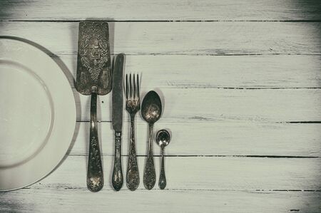 Vintage cutlery on a white wooden surface, empty space, retro toning