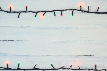 electric Christmas garland with colored small bulbs on a white wooden surfaceの写真素材