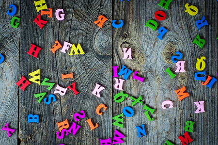 Multicolored little wooden letters on a gray surface, full frameの写真素材