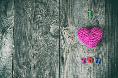 Abstract gray background with wooden sign and a red knitted heart shape, empty spaceの写真素材