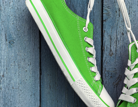 Bright green textile sneakers hanging on the white lace, blue wood backgroundの写真素材