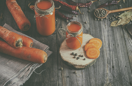 Fresh carrot juice with pulp among the vegetables and spices, vintage toningの写真素材