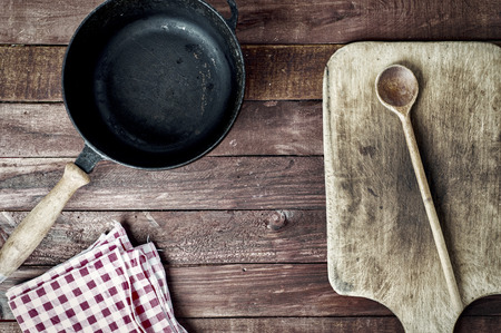 empty black metal pan and cutting board on a wooden surface, top viewの写真素材