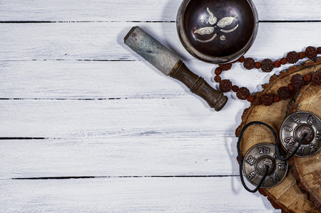 Singing bowl and other religious objects for meditation and relaxation, white wooden background, empty space on the leftの写真素材