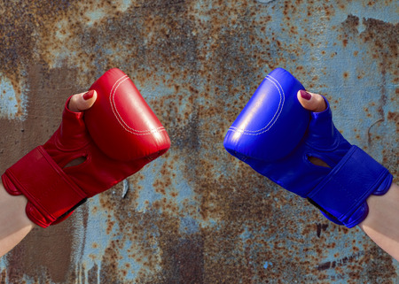 Two female hands in red and blue boxing gloves, hands are on opposite sidesの写真素材