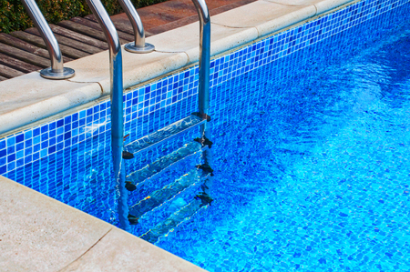 Iron staircase in the pool with blue tiles, full water poolのeditorial素材