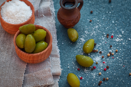 Green olives and olive oil in a clay pitcher, near salt and pepper, top viewの写真素材