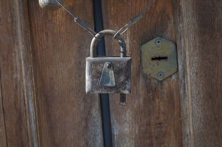 Old rusty closed lock against the brown door