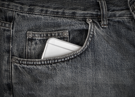 Smartphone in the front pocket of black jeans, close up