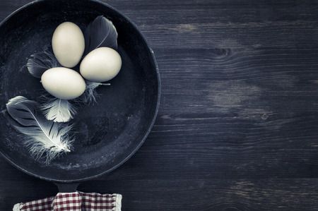 Raw eggs in a black frying pan, top view, empty space on the right