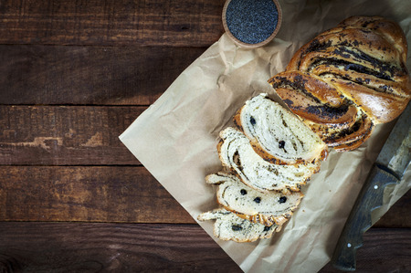Sweet roll with poppy seeds sliced on brown kraft paper, top view, empty space on the leftの写真素材