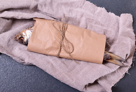 dried fish roach wrapped in brown craft paper on a black surfaceの写真素材