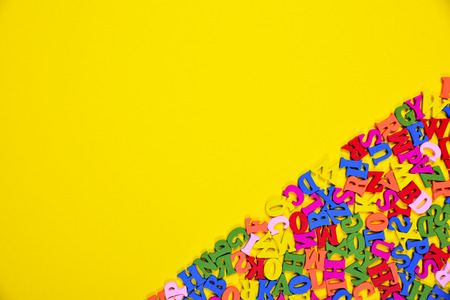 Abstract yellow background with multicolored letters of the English alphabet, blank space on the...