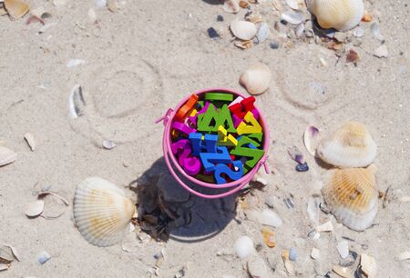 Iron pink bucket full of wooden multicolored letters, top view, sea beachの写真素材