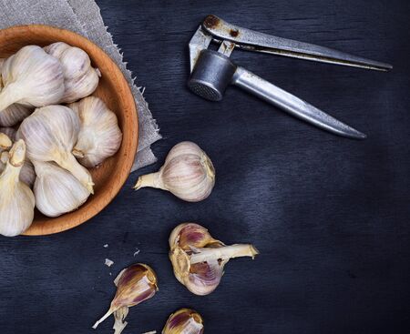 Fruits of garlic in a wooden bowl and on a black table, top viewの写真素材