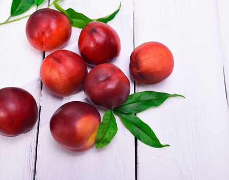 Fresh red peaches on a white wooden background, top viewの写真素材