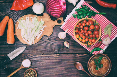 Plate with borscht and food for cooking on a brown background, empty space in the middleの写真素材