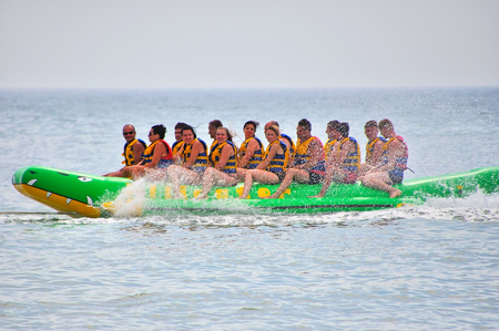 Village Lazurnoe of the Kherson area, Ukraine, August 18, 2017: smiling group of people in vests riding on inflatable structures on a summer dayのeditorial素材