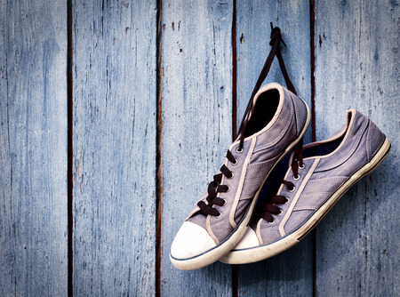 a pair of old man's dirty blue sneakers hanging on a wooden wall, empty spaceの写真素材