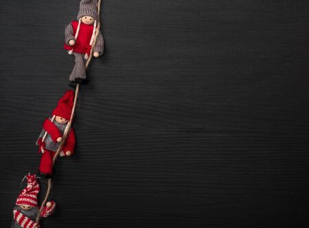 black wooden background with wooden puppets on a rope, empty space on the rightの写真素材