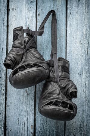black leather gloves for kickboxing hang on a rope on a blue wooden backgroundの写真素材