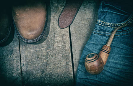 Casual clothing with wooden smoking pipe on a wooden surface, top view, an empty space, vintage toningの写真素材